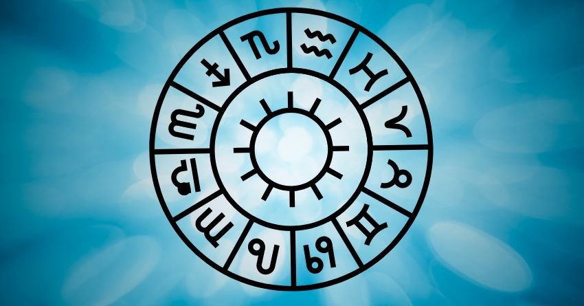 Blue zodiac wheel with astrological symbols surrounding a central sun on a bright cosmic background