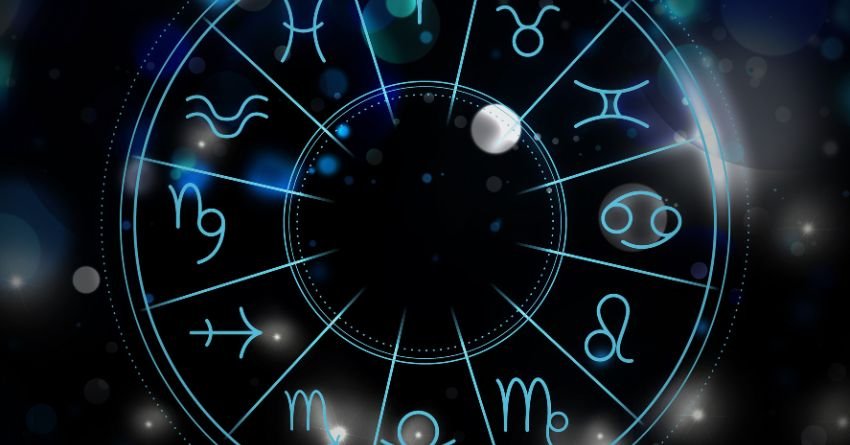 Dark blue zodiac wheel with glowing astrological symbols on a mysterious cosmic background