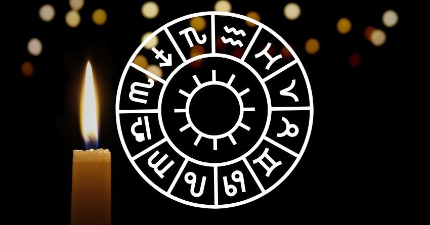 Glowing zodiac wheel with astrological symbols against a dark background with warm golden lights