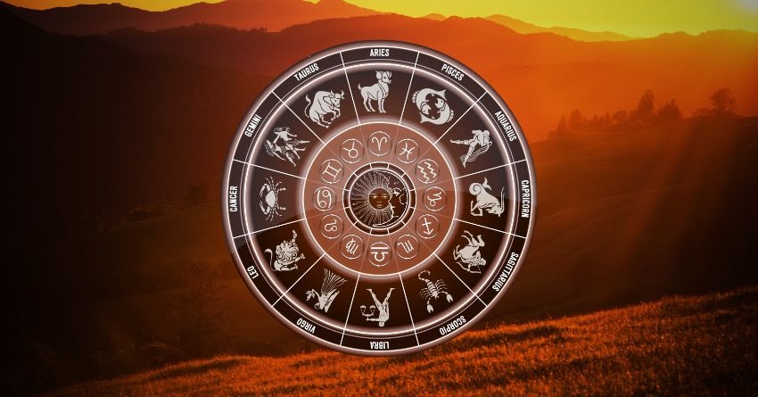 Glowing zodiac wheel with astrological symbols above a dark orange landscape and dramatic sunset sky